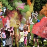 Festiwal kolorów. Dzieci rozrzucają kolorowe proszki w górę.